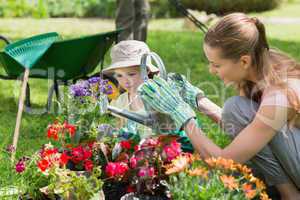 Mother and daughter watering plants at garden