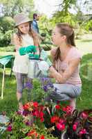 Mother with daughter watering plants