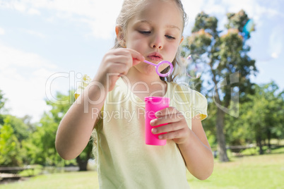 Girl blowing soap bubbles at park