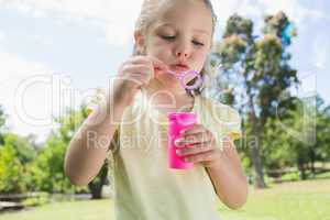 Girl blowing soap bubbles at park