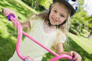 Little girl on a bicycle at summer park