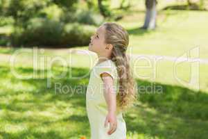 Girl with arms outstretched looking upwards at park