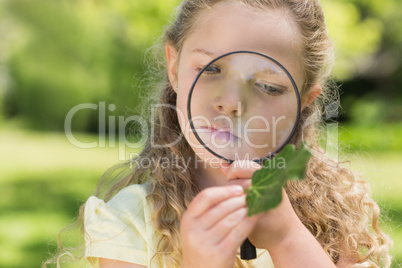 Girl examining leaf with magnifying glass at park