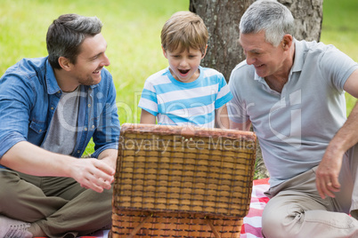 Grandfather father and son with picnic basket at park