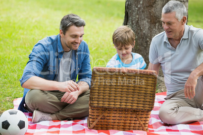 Grandfather father and son with picnic basket at park