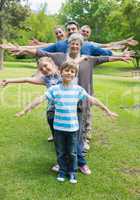 Extended family standing in row with arms outstretched at park