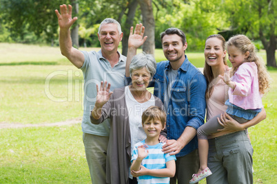 Happy extended family waving hands at park