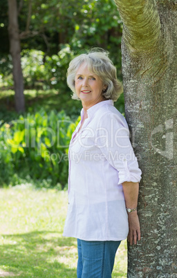 Portrait of a mature woman leaning against tree trunk