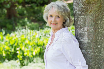 Portrait of a mature woman leaning against tree trunk