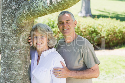 Smiling mature couple besides tree at park