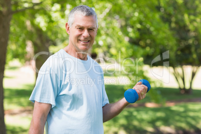 Smiling mature man with dumbbell at park