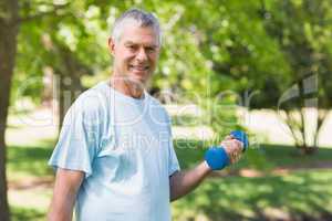 Smiling mature man with dumbbell at park
