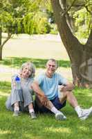 Mature couple sitting with water bottles at park