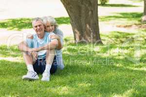 Mature couple sitting on grass at park