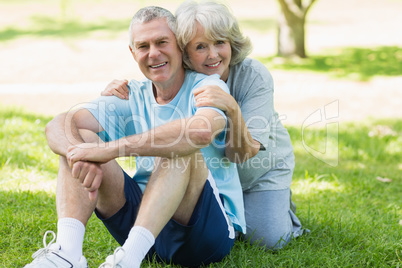 Smiling mature couple sitting on grass at park