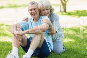 Smiling mature couple sitting on grass at park