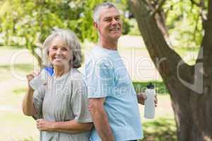 Smiling mature couple with water bottles at park