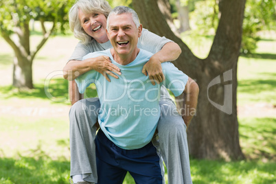 Cheerful mature man carrying woman at park