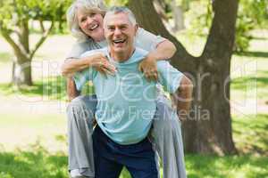 Cheerful mature man carrying woman at park