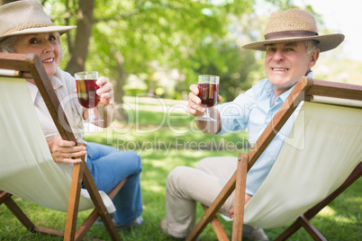 Relaxed mature couple with wine glasses at park