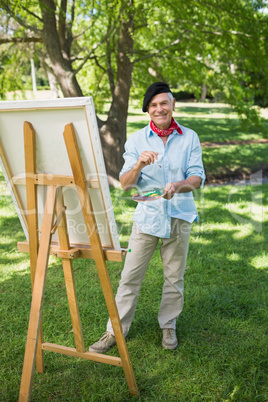 Mature man painting on canvas in park