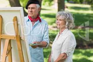 Woman watching mature man paint in park