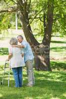 Mature man assisting woman with walker at park