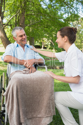 Woman with father sitting in wheel chair at park