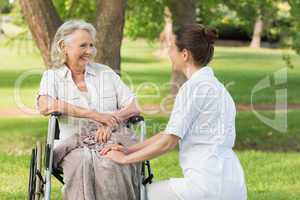 Woman with her mother sitting in wheel chair at park