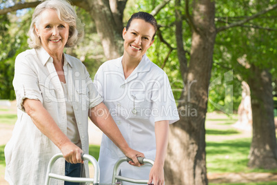 Female assisting mature woman with walker at park