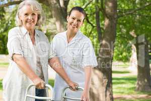 Female assisting mature woman with walker at park