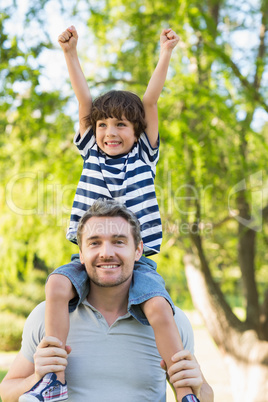 Father carrying a happy son on shoulders at park