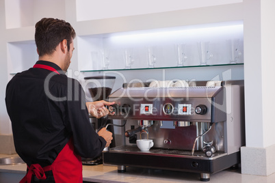 Handsome young barista making a cup of coffee