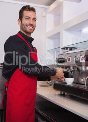 Cheerful young barista making cup of coffee