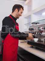 Happy young barista making cup of coffee