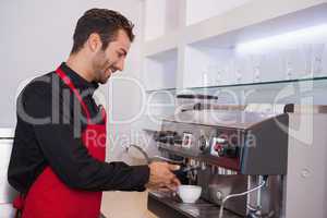 Happy attractive barista making cup of coffee