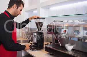 Handsome barista grinding coffee beans