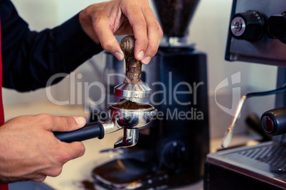 Barista pressing fresh coffee grounds