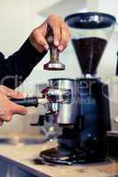 Barista pressing down fresh coffee grounds