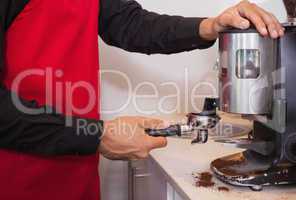 Barista using coffee grinder to grind coffee beans