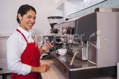 Pretty barista making coffee smiling at camera