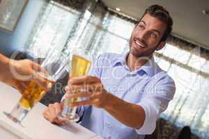 Smiling businessman clinking glass of beer with bartender