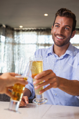 Happy businessman clinking glass of beer with bartender