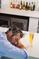 Drunk businessman sleeping beside glass of beer