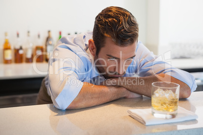 Drunk businessman looking at his whiskey glass after work