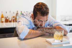 Drunk businessman looking at his whiskey glass after work