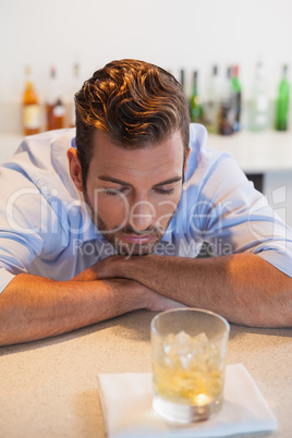 Drunk businessman looking at his whiskey glass