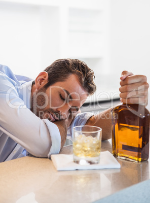 Drunk businessman clutching whiskey bottle asleep