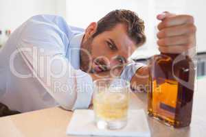 Drunk businessman clutching whiskey bottle looking at camera