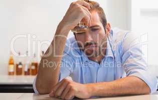 Drunk businessman clutching whiskey glass to head